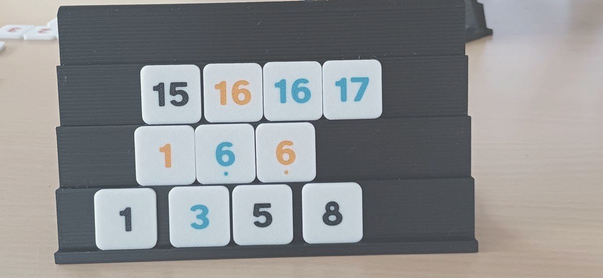 Schwarze Spielbank mit Zahlensteinen in Schwarz, Gelb und Blau in drei Reihen