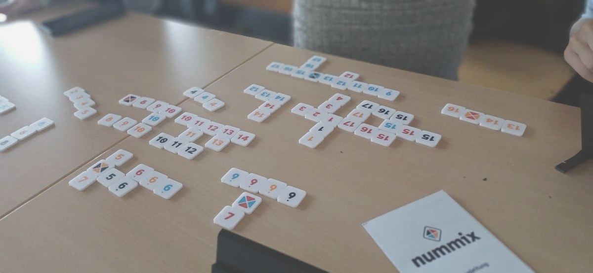 Spieltisch mit vielen gelegten Reihen, vorn die Spielanleitung