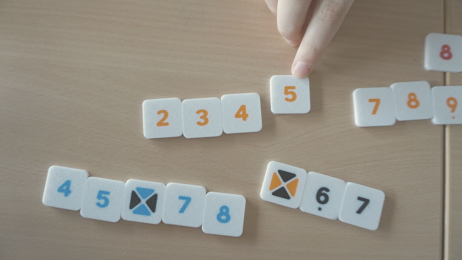 Eine Hand legt einen Spielstein an eine Zahlenreihe